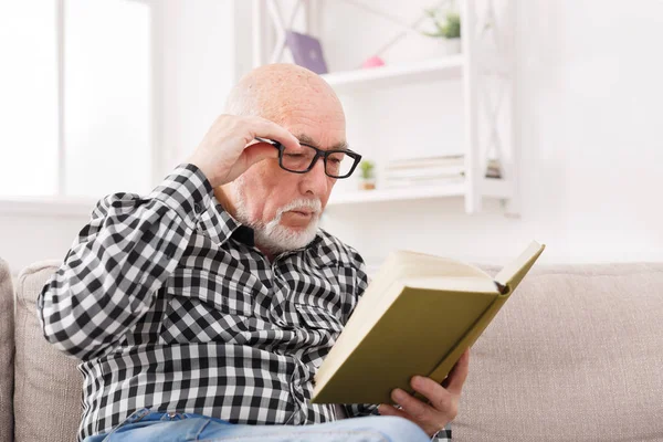 Senior Mann liest Buch zu Hause, Kopierraum — Stockfoto