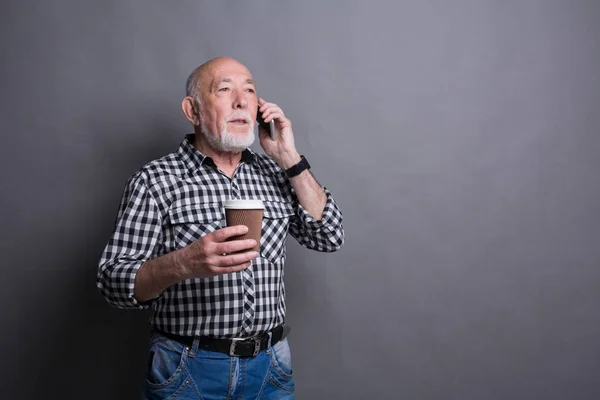 Ocupado homem sênior falando no telefone com xícara de café — Fotografia de Stock