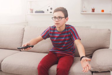 Televizyon izlerken, uzaktan kumanda ile genç çocuk