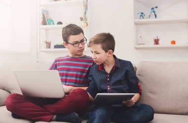 İki genç çocuklar evde kanepede gadget'lar ile