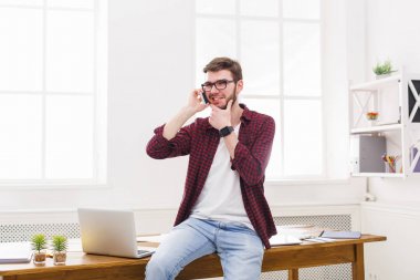 Konsantre genç işadamı modern beyaz ofiste bir telefon konuşma vardır