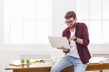 Genç işadamı modern beyaz ofis içinde laptop ile vurguladı
