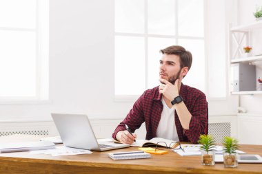 Dalgın genç işadamı notlar modern beyaz ofiste alır.