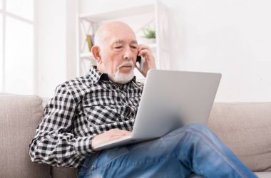 Dizüstü bilgisayar ile telefonda konuşan üst düzey adam