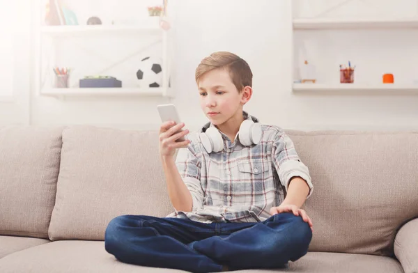 Mensajería adolescente en línea en el teléfono inteligente en la sala de estar en casa —  Fotos de Stock
