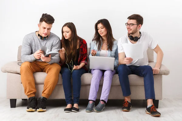 Diversos estudiantes que utilizan aparatos, sentarse en el sofá — Foto de Stock