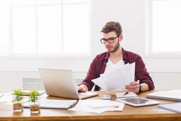 Ung koncentrerad affärsman med laptop i modern vit office — Stockfoto