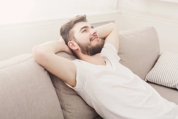 Pohledný mladý muž relaxační na gauči doma — Stock fotografie