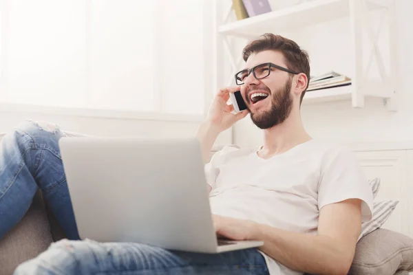 Sonriente joven en casa con portátil y móvil — Foto de Stock