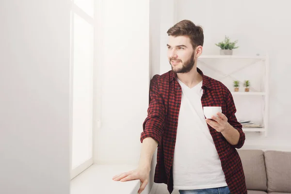 Joven hombre sonriente bebiendo café en casa — Foto de Stock