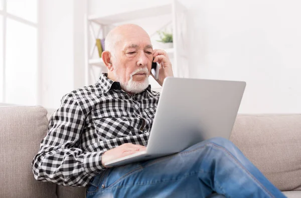 Dizüstü bilgisayar ile telefonda konuşan üst düzey adam