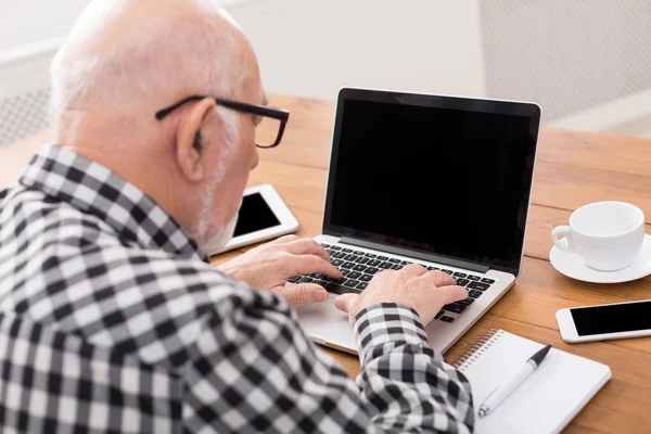 Hombre mayor usando portátil con maqueta de pantalla en blanco — Foto de Stock