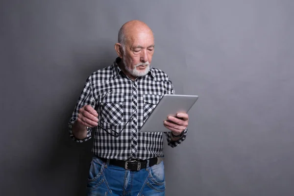 Homem sênior lendo notícias no tablet digital — Fotografia de Stock