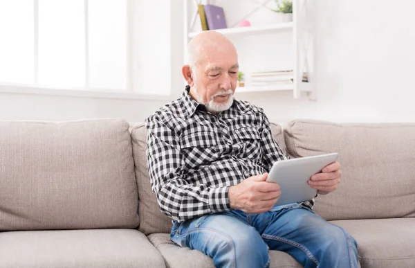 Старший чоловік читає новини на цифровому планшеті — стокове фото