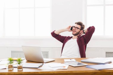 Genç memnun işadamı bir telefon konuşma modern beyaz ofiste vardır.