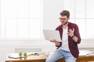 Genç işadamı modern beyaz ofis içinde laptop ile vurguladı