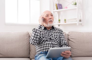 Tablet ile telefonda konuşan üst düzey adam