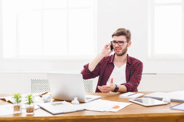 Jovem empresário concentrado tem uma conversa móvel no escritório branco moderno — Fotografia de Stock