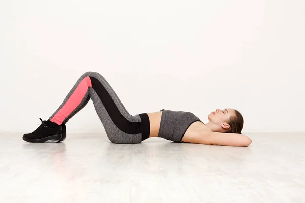 Mujer de fitness yacía en el suelo en el entrenamiento de pilates en interiores — Foto de Stock