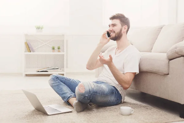 Sonriente joven en casa con portátil y móvil — Foto de Stock