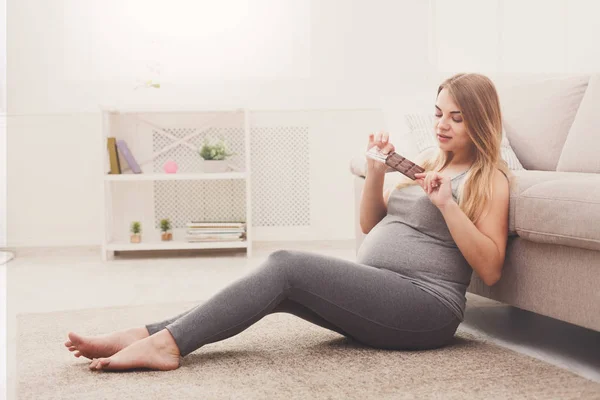 Беременная женщина наслаждается шоколадным батончиком — стоковое фото