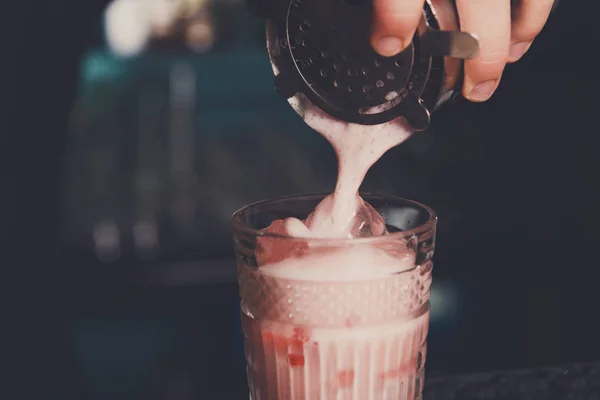 Молодой бармен наливает коктейль в стакан — стоковое фото
