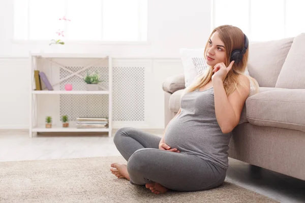 Mulher grávida ouvindo música em fones de ouvido — Fotografia de Stock