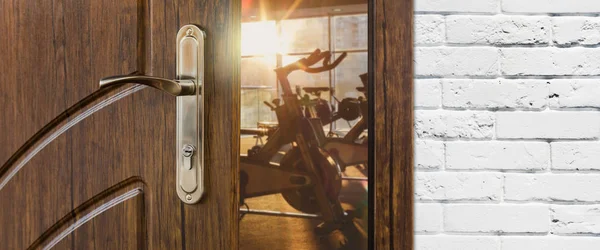 Entrance to gym in fitness club, opened door with exercise bikes — Stock Photo, Image