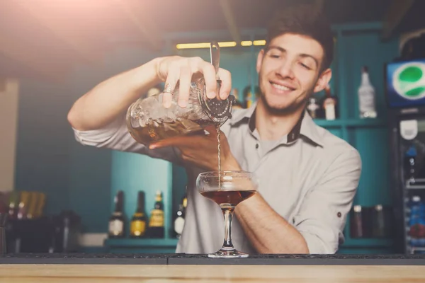 Jovem barman derramando bebida de coquetel em vidro — Fotografia de Stock