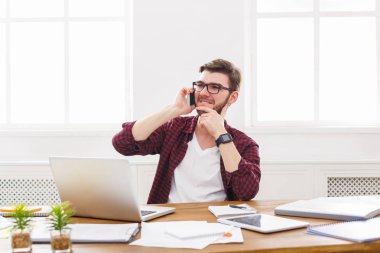 Genç memnun işadamı bir telefon konuşma modern beyaz ofiste vardır.