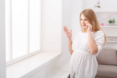 Gülümseyen hamile kadın onun smartphone üzerinde söz