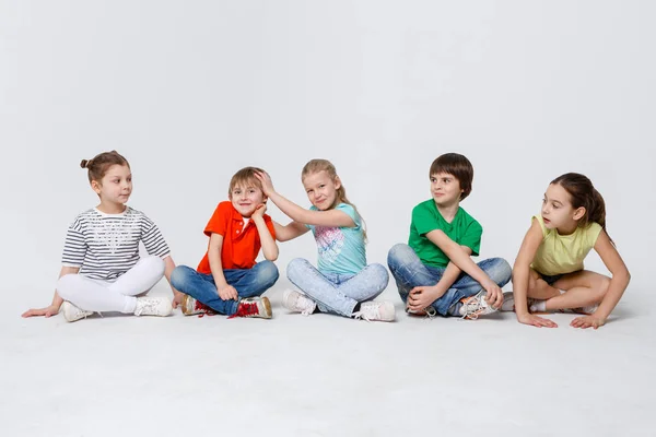 Lykkelige barn som sitter på gulvet i studio, kopierer plass – stockfoto