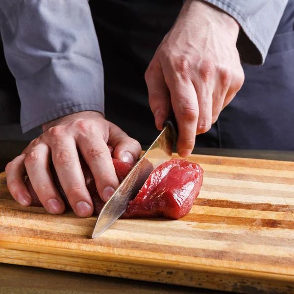 Chef cutting filet mignon on wooden board at restaurant kitchen — Stock Photo, Image