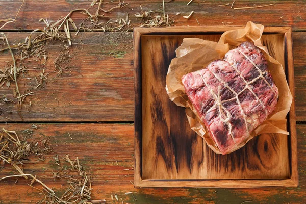 Raw aged prime black angus beef in craft papper on rustic wood — Stock Photo, Image