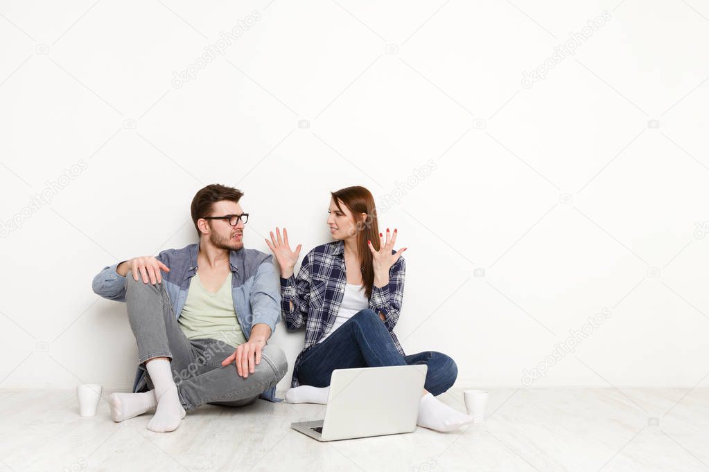 Casual couple discuss something unpleasant sitting with laptop, studio shot
