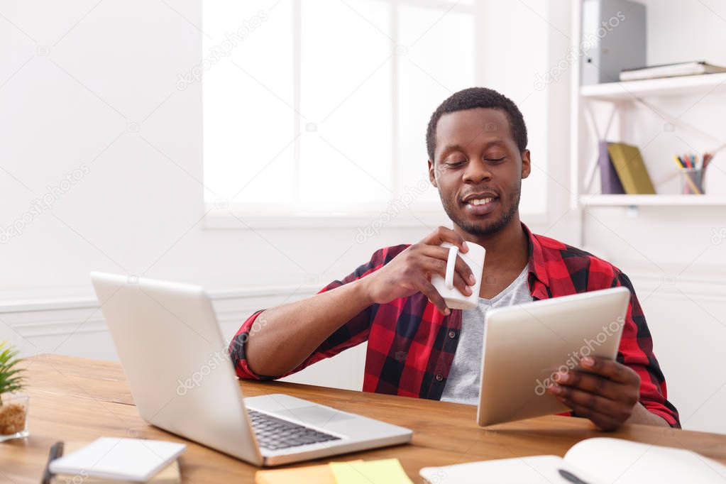 Young black businessman with mobile phone in modern white office