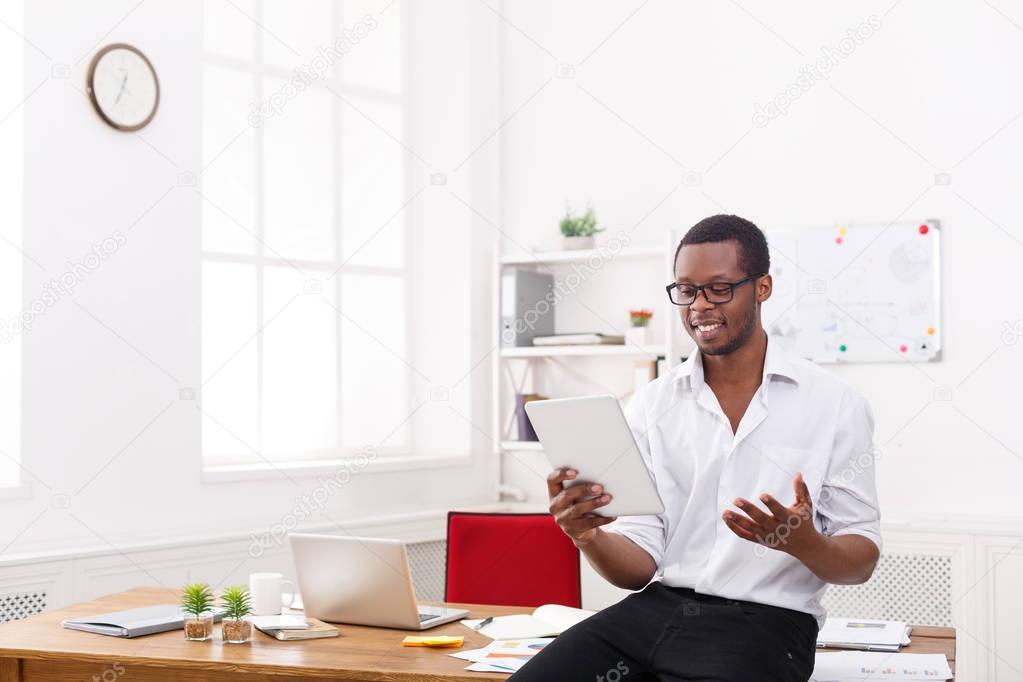 Happy black businessman in modern office, work with tablet