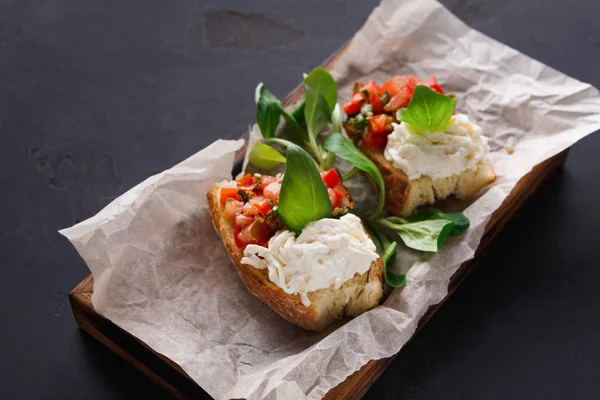 Bruschetta com queijo e legumes sobre fundo preto — Fotografia de Stock