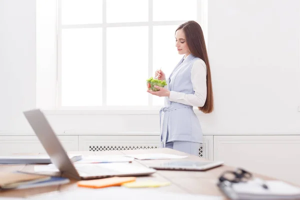 Joven mujer de negocios comiendo ensalada en la oficina —  Fotos de Stock