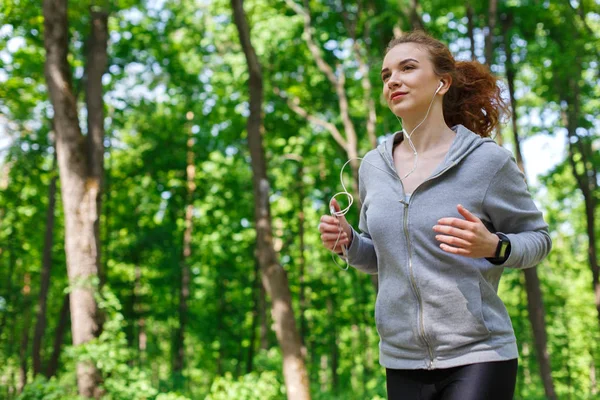 Vrouw luisteren muziek tijdens het lopen in het park Stockafbeelding