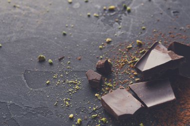 Kırık çikolata parçaları ve siyah arka plan üzerine kakao tozu