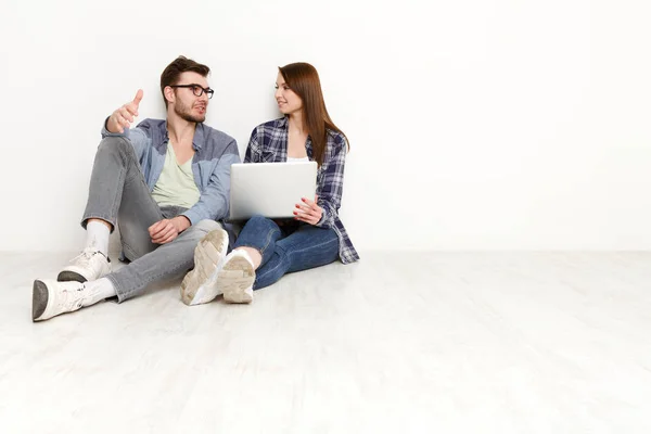Casual par diskutera något sitter med laptop, studio skott — Stockfoto