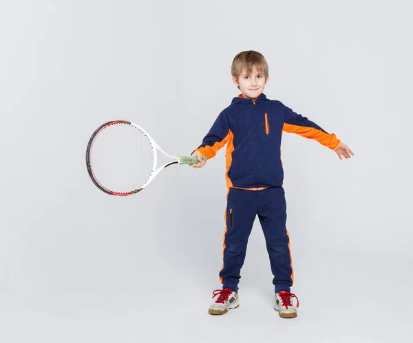Malý roztomilý tenista v oblečení s raketou na studio pozadí — Stock fotografie