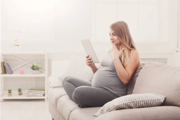 Счастливая беременная женщина с помощью цифрового планшета . — стоковое фото