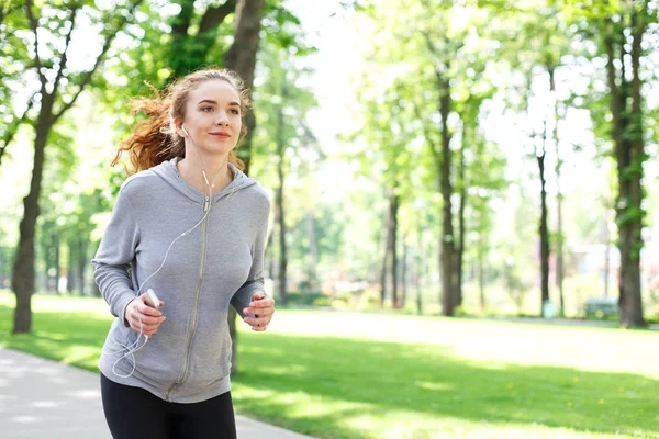 Young woman jogging in green park, copy space Stock Picture
