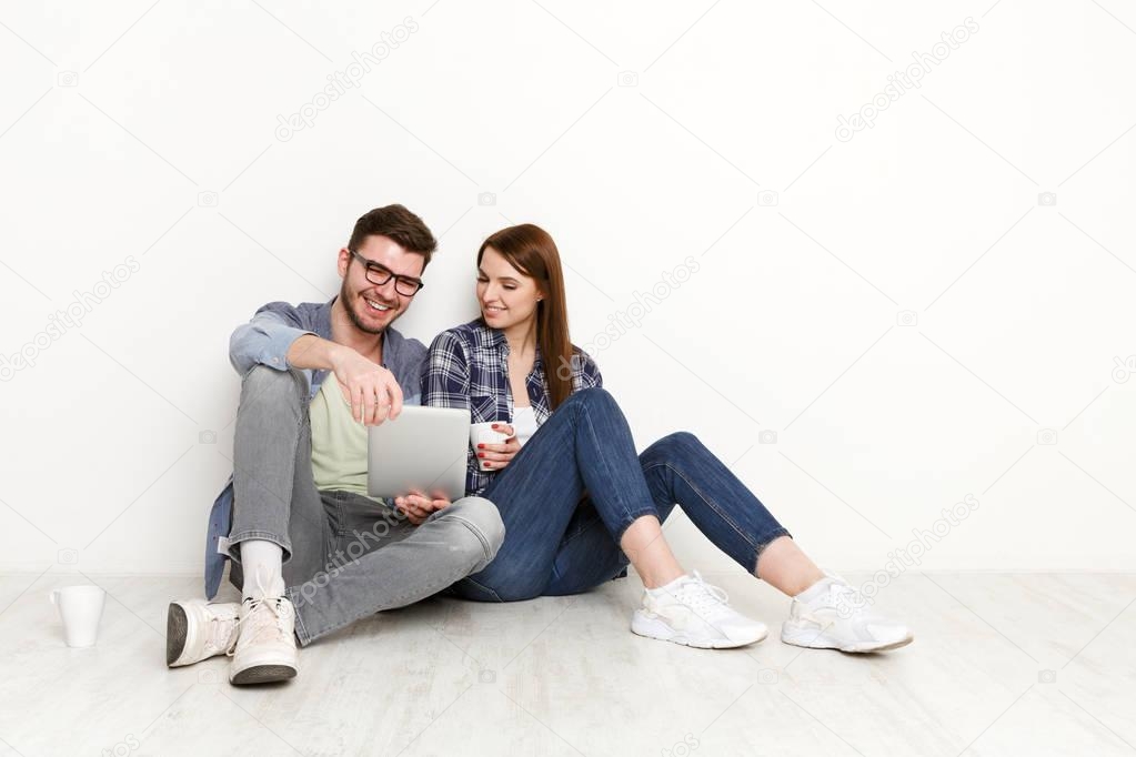 Happy couple shopping online, sitting on floor at home