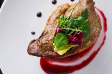 Restoran yemekleri. Ördek confit siyah arka plan üzerine sebzeli