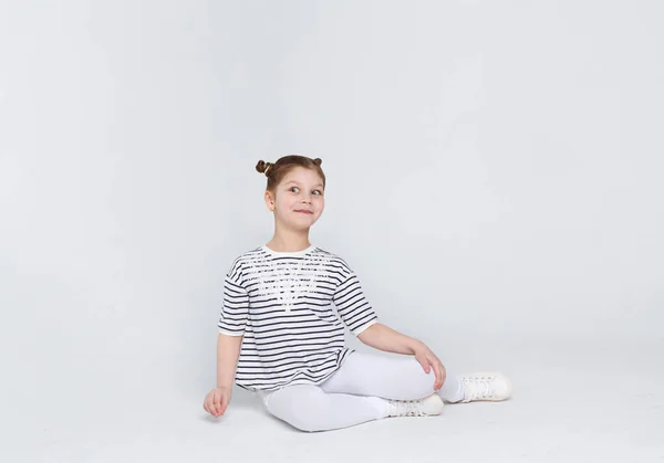 Retrato de chica divertida asombrada sentada en el suelo sobre fondo blanco — Foto de Stock