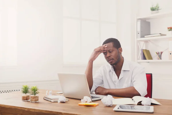 Moe zwarte zakenman in kantoor, werken met een laptop — Stockfoto