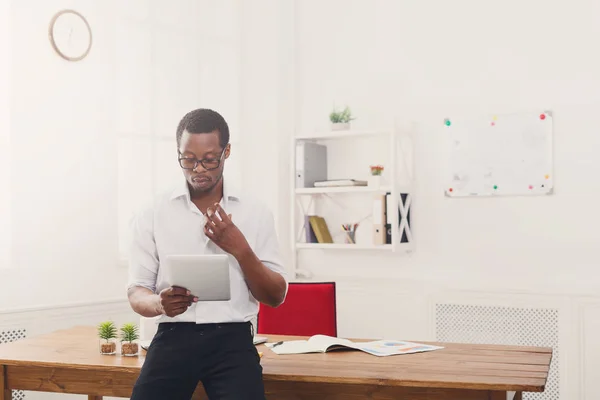 Homem de negócios preto concentrado no escritório moderno, trabalho com tablet — Fotografia de Stock